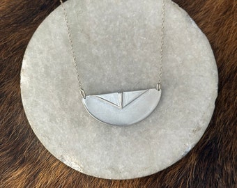 The “Adrian” necklace of a half circle with two triangles layered up on the necklace pendant