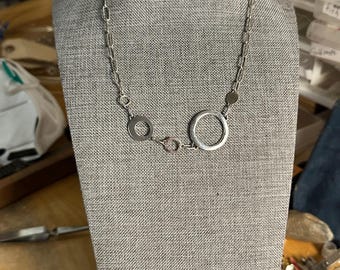 Alicia link necklace with five different sized circles with different characteristics, wire framed circles solid circle and cut out circle