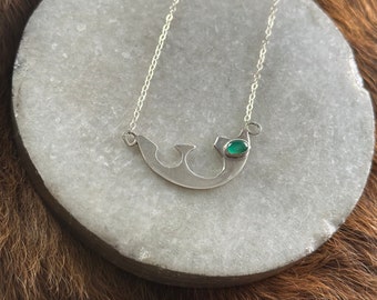 Ingrid necklace, an irregular swooping sterling silver metal shape with small green onyx stone