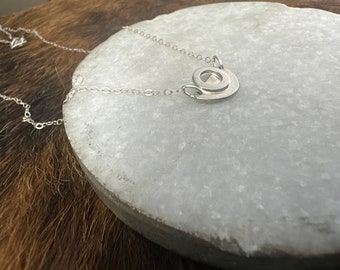 The Adrian necklace made of one small sized half circle and a small circle layered on the necklace focal point