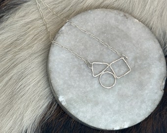 Geo necklace is framed circle, triangle and square shapes clustered and made in sterling silver with hammered finish
