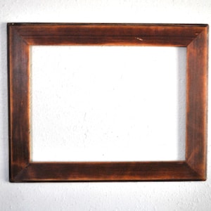 May include: A rectangular wooden picture frame with a dark brown finish. The frame has a simple, classic design and is empty, with a white interior. The frame is likely for displaying photos or artwork.