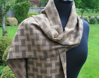 May include: A brown and black patterned scarf with fringe. The scarf is draped around a black mannequin.