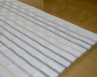 May include: White table runner with a checkered pattern and thin stripes in shades of gray, pink, and yellow.