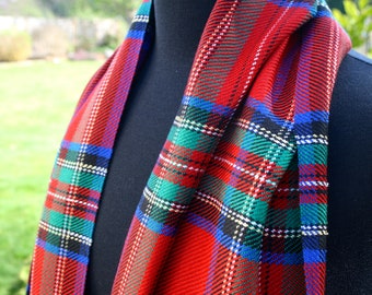 May include: A red, green, blue, and white plaid scarf with a fringed edge. The scarf is folded and draped over a black mannequin.