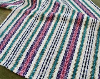 May include: White fabric with teal, pink, and navy blue stripes. The stripes have a woven diamond pattern.