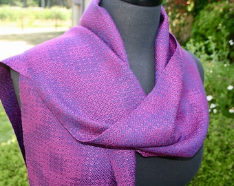 May include: A purple and blue woven scarf with a diamond pattern. The scarf is draped over a mannequin.