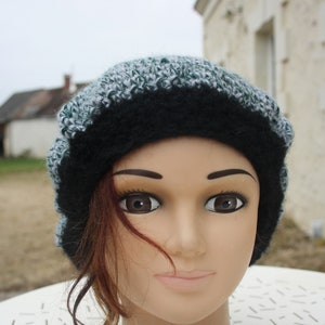 Peut inclure: Un bonnet en tricot noir et blanc avec une bande verte. Le bonnet est sur une tête de mannequin avec des cheveux bruns.