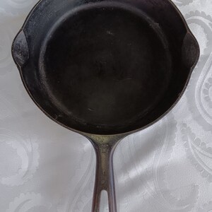 May include: A black cast iron skillet with a long handle. The skillet is empty and has a smooth surface.