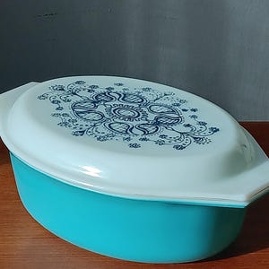 May include: A turquoise blue oval casserole dish with a white lid. The lid has a blue and white floral design.