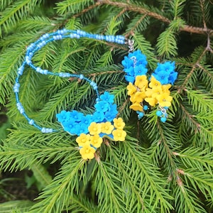 Orecchini gialli e blu con piccoli fiori e un ciondolo a farfalla