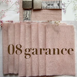 May include: A swatch of dusty pink fabric with a visible woven texture, featuring the text 08 garance in brown. A measuring tape is positioned at the top, showing a measurement of 1 inch or 2.5 centimeters across the width of the fabric sample.