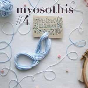 Gros plan sur des fournitures de broderie, notamment des fils bleu clair et blancs, une pelote et une petite carte avec "Dyeing2meetU". Le mot "myosothis" et le numéro "4" sont imprimés sur l'image. Un cercle à broder avec un motif floral est également visible.