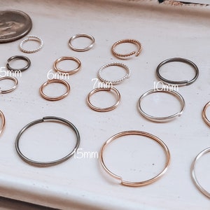 May include: A set of 10 hoop earrings in various sizes, ranging from 4mm to 15mm. The hoops are made of silver, gold, and black metal.
