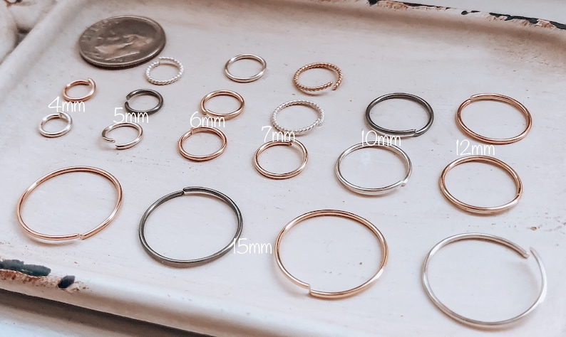 May include: A set of 10 hoop earrings in various sizes, ranging from 4mm to 15mm. The hoops are made of silver, gold, and black metal.