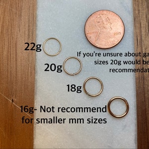 May include: Four gold hoop earrings of different sizes, labelled 22g, 20g, 18g, and 16g. The 16g hoop is labelled "Not recommend for smaller mm sizes". A penny is included for size reference.  "If you're unsure about gauge sizes 20g would be my recommendation."