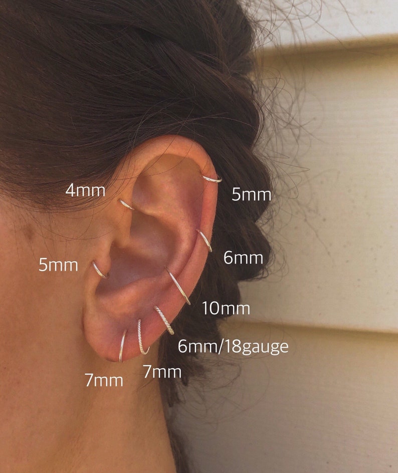 May include: Close-up of a person's ear with multiple silver hoop earrings in different sizes, including 4mm, 5mm, 6mm, 7mm, 10mm, and 6mm/18 gauge.