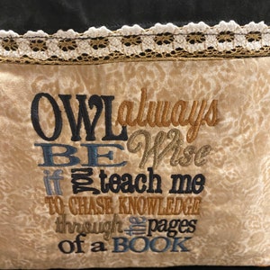 May include: A decorative pillow with embroidered text. The text reads "OWL always BE Wise if teach me TO CHASE KNOWLEDGE through pages of a BOOK." The pillow has a beige background with a floral pattern, black trim, and a lace border.