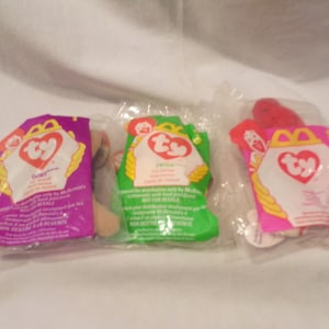 May include: Three Ty Beanie Babies in their original packaging. The beanie babies are named "Dory", "Twinkle", and "Splatter". The packaging is pink, green, and red.
