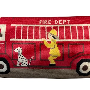 May include: A red needlepoint pillow featuring a fire truck design. The pillow has a white ladder, the words "FIRE DEPT", and a firefighter in yellow. A dalmatian dog is also featured. The number "5" is visible on the side of the truck.