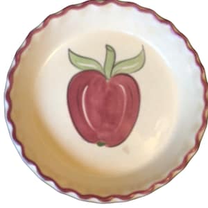May include: A white ceramic pie plate with a scalloped edge and a red apple design. The apple is painted in shades of red and green.