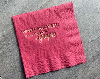 Puede incluir: Una servilleta de tela roja con letras doradas que dicen "Wine Hangovers: the evil wrath of grapes".