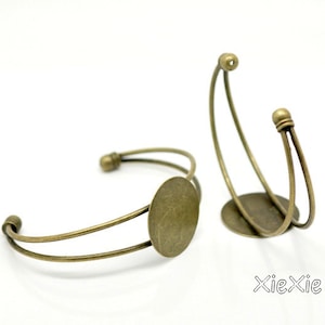 Könnte beinhalten: Zwei antike goldfarbene Metall-Armreifen mit einer runden Fassung für ein Kamee oder einen anderen Schmuck.