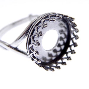 May include: Silver ring with a round bezel setting. The bezel has a decorative design around the edge.