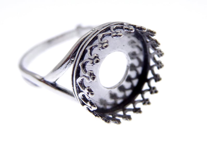 May include: Silver ring with a round bezel setting. The bezel has a decorative design around the edge.