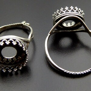 May include: Two silver adjustable ring settings with a round bezel. The bezels have a decorative crown design.
