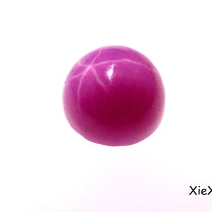 Könnte beinhalten: Ein rosafarbener Sternrubin-Edelstein mit einem sechszackigen Sternmuster.