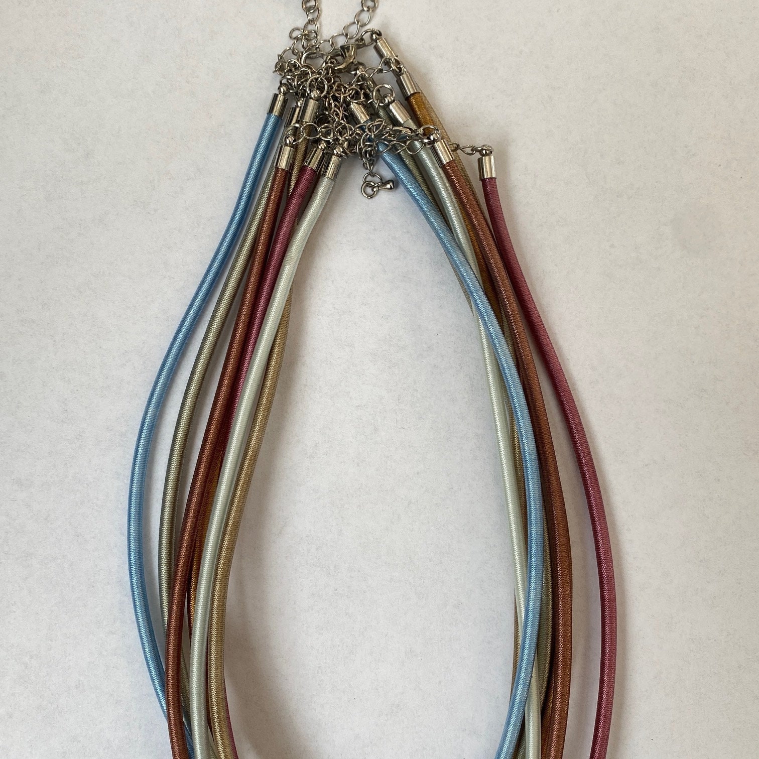Assortment of 7 satin corded necklace in various colors. 17" plus 2" extender