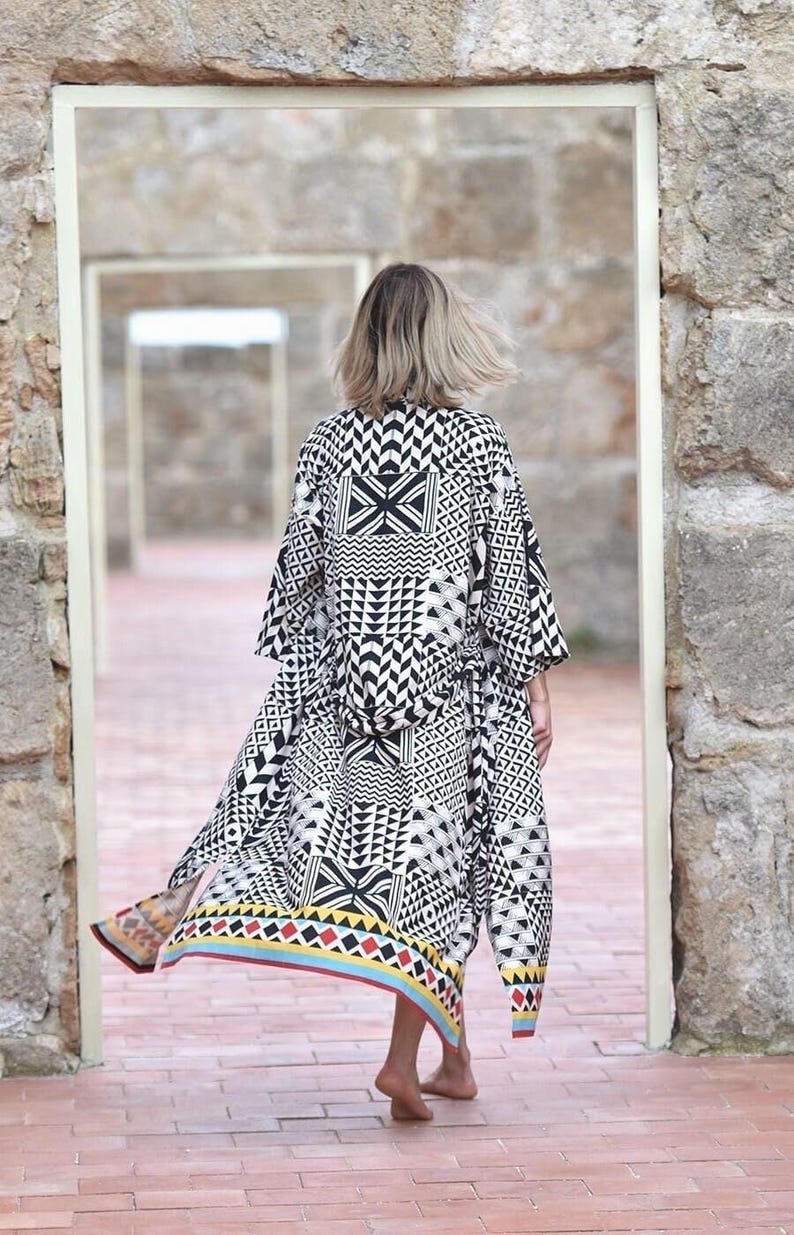 Beige boho kimono with black geometric tribal print and vibrant red, yellow, and blue border. Elegantly tailored for a flattering fit, featuring versatile inside ties. Hand screen printed with Azo-free, earth-friendly dyes. Ideal for loungewear, travel, festivals, and maternity wear.