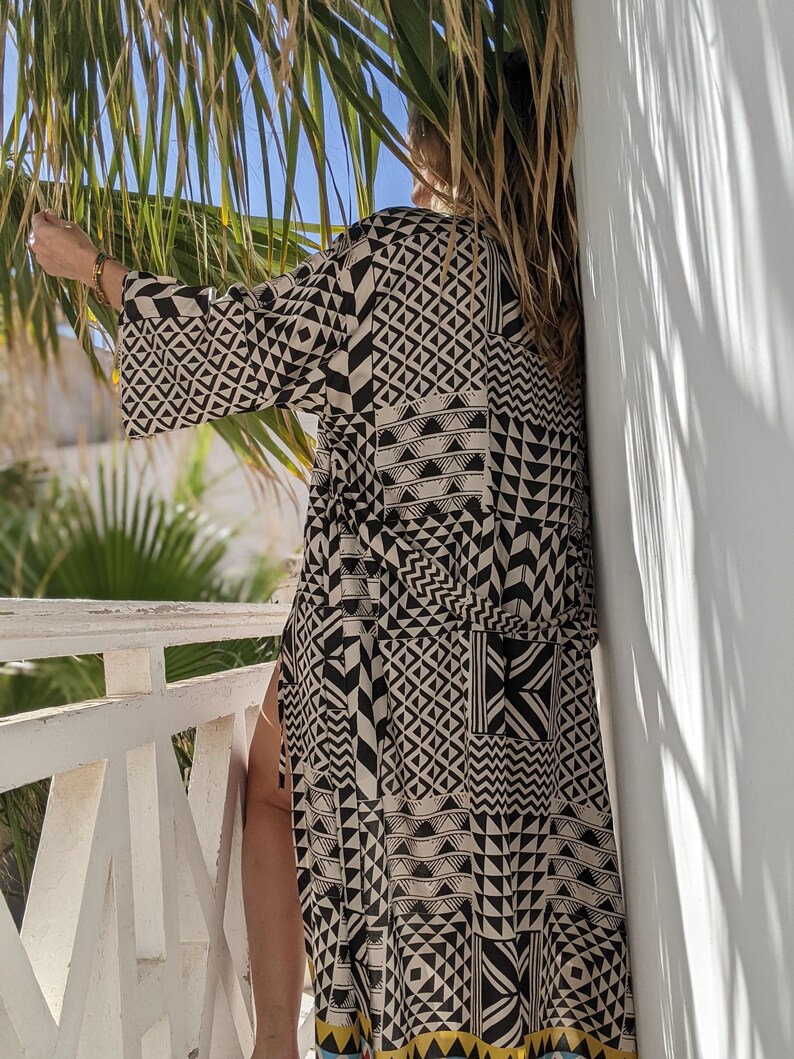May include: A black and white geometric patterned kimono with a long sleeve and a sash tie. The kimono is made of a lightweight fabric and has a relaxed fit.
