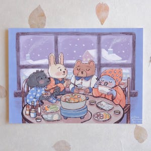 May include: Illustration of four anthropomorphic animals gathered around a table, enjoying a meal. The scene is set in a snowy environment, with a window showing a winter landscape. The animals include a dog, rabbit, bear, and koala.
