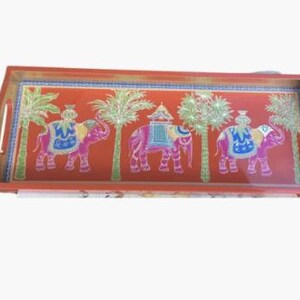 May include: Rectangular serving tray with a vibrant orange background. The tray features three elephants with colorful saddles and palm trees. The tray has a wooden frame with handles.