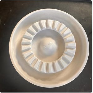 Può includere: Posacenere in ceramica bianca con un anello interno scanalato e un anello esterno liscio.