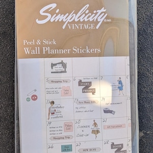 May include: A package of Simplicity Vintage Peel & Stick Wall Planner Stickers, model W12489. The clear plastic sleeve contains a grid sheet featuring various sewing-themed illustrations, text labels, and icons for calendar organization.
