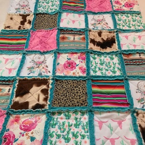May include: A patchwork quilt featuring squares of various patterns and textures. Designs include floral prints, cowhide, leopard print, and Southwestern motifs. The quilt is bordered with teal fabric and has a soft, textured appearance.