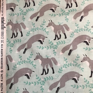 May include: A light blue fabric with a repeating pattern of gray foxes and green leaves. The foxes are depicted in various poses, including sleeping, jumping, and standing. The text "Le Amis by Patty Sloniger for michael miller FABRICS LLC. ALL RIGHTS RESERVED PATT# PS5794 Socks the Fox" is printed on the left side of the fabric.