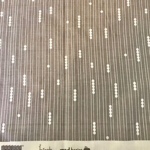 May include: Gray fabric with a white vertical stripe and dot pattern. The fabric has the text "jay-cyn", "birch fabrics", "mod basics", and "100% Organic Cotton" printed on the bottom edge.