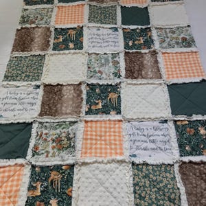 May include: A patchwork baby quilt with various fabric squares in shades of green, brown, and orange. Some squares feature deer, floral, and gingham patterns. The quilt includes the text: "A baby is a blessing gift from heaven above a precious little angel to cherish and to love."