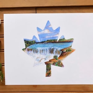 May include: A watercolor painting of a waterfall scene inside a maple leaf shape. The painting is on white paper and has a blue sky, green trees, and a white waterfall.