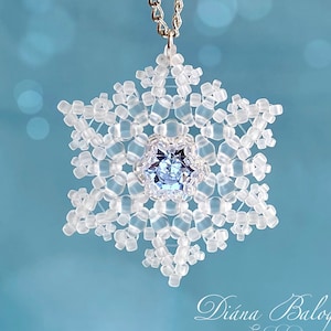 May include: A delicate snowflake pendant necklace made with clear beads and a light blue crystal in the center. The necklace is on a silver chain.