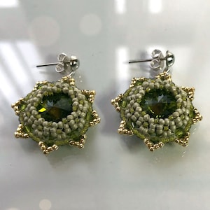May include: A pair of green and gold beaded earrings with a crystal center. The earrings are on a white surface.