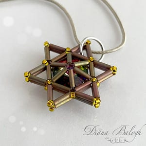 Puede incluir: Un collar con colgante en forma de estrella con una cadena plateada. El colgante está hecho de cuentas marrones y doradas, con un cuadrado iridiscente central. Las cuentas están dispuestas en un patrón geométrico, creando una estrella tridimensional. Una joya delicada.