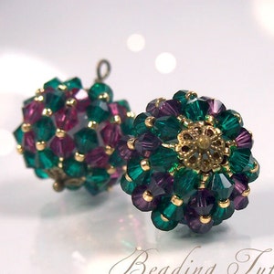 Può includere: Un paio di orecchini con perline verdi e viola, dettagli dorati e un design a fiore di perline.