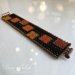 Puede incluir: Un brazalete de cuentas negras con detalles en naranja, rojo y dorado. El brazalete tiene un patr&oacute;n geom&eacute;trico y se asegura con un cierre de metal.