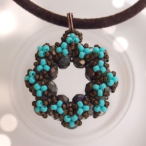 May include: A turquoise and brown beaded pendant necklace with a geometric design. The pendant is shaped like a circle with a starburst pattern.