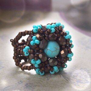 Pode incluir: Um anel de contas marrons e turquesa com uma pedra turquesa no centro.